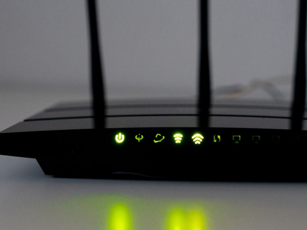 Painel frontal de roteador com luzes verdes acesas, indicando funcionamento e como melhorar a internet do Wi-Fi.