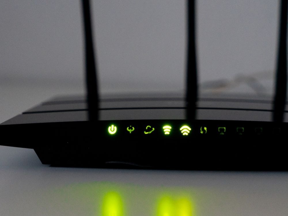 Luzes indicadoras de roteador Wi-Fi em funcionamento, reforçando que a velocidade da internet depende do roteador e do desempenho do equipamento.