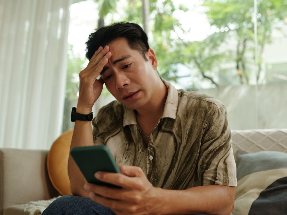 Homem preocupado usando celular representa problemas de Internet lenta como resolver falhas de conexão e instabilidade no sinal da rede.