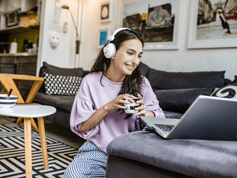 Pessoa joga em um notebook usando headset no ambiente doméstico, ilustrando o uso de internet residencial para jogos online.