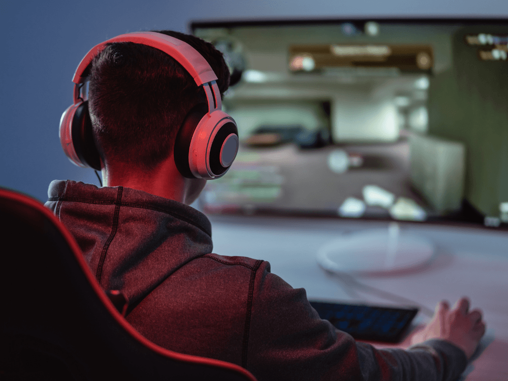 Jogador utiliza headset diante de um monitor durante partida competitiva, demonstrando a importância de uma conexão rápida e estável.