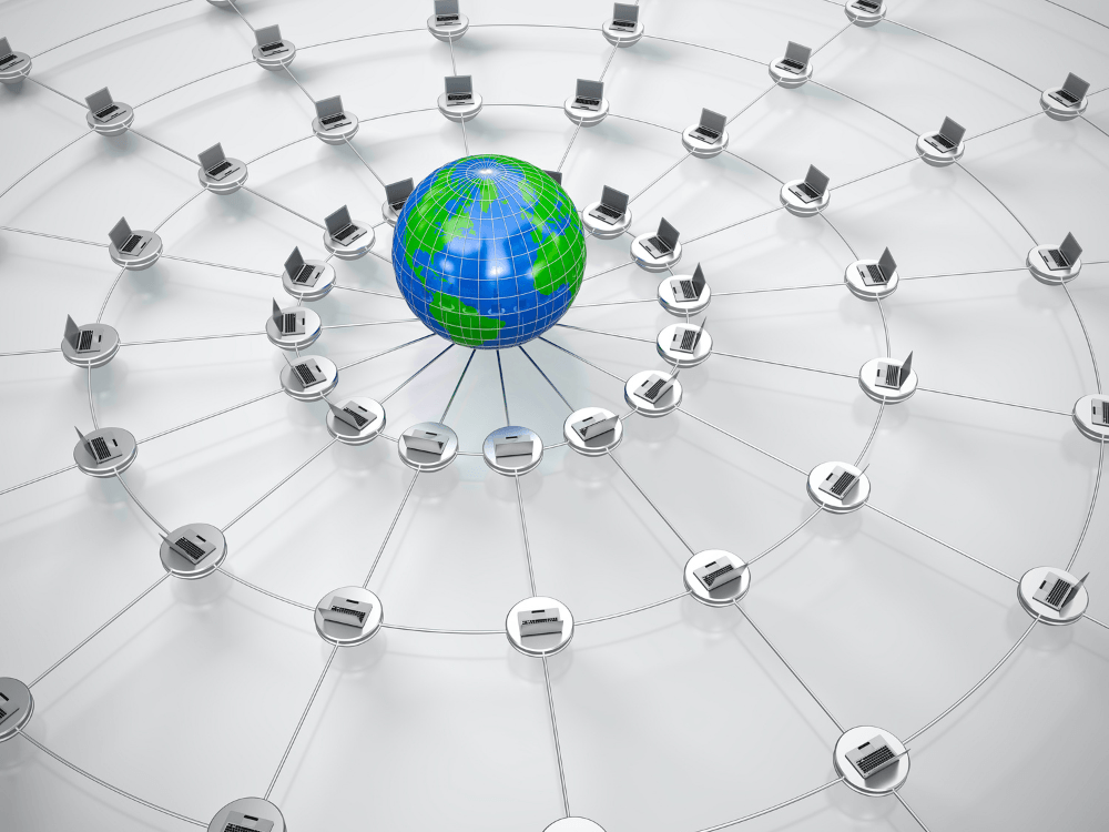 Computadores interligados em uma topologia de rede ao redor de um globo, representando o compartilhamento de informações.